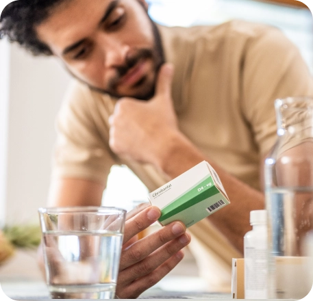 Jeune homme regardant attentivement une boite de médicaments